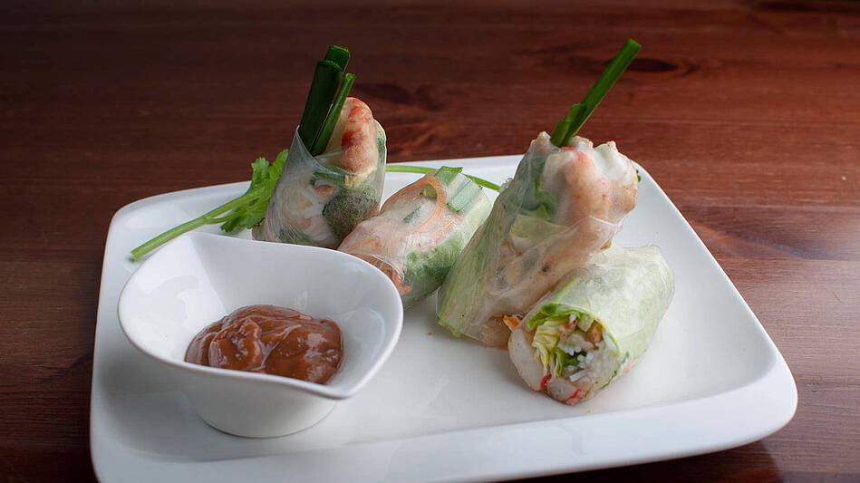 Two Vietnamese summer rolls served with vegetables and a peanut dip
