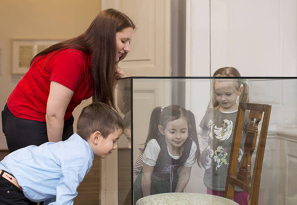 drei Kinder und eine junge Frau schauen sich ein Ausstellungsstück an
