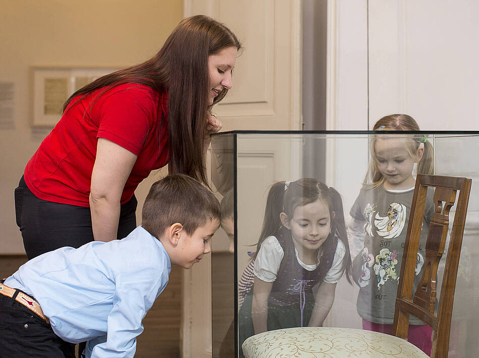 drei Kinder und eine junge Frau schauen sich ein Ausstellungsstück an